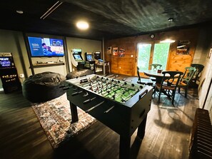 Een kamer met een tafelvoetbaltafel, een televisie en spelautomaten.