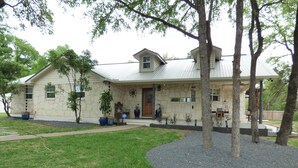 A stone house with a metal roof, a front porch, and a well-maintained lawn. - PENION HOME! HOT TUB FOR 6/7 - SPACIOUS YARD FOR KIDS! (Austin)
