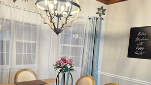 A dining area with a wooden table, chairs, a chandelier, and a decorative centerpiece. - PENION HOME! HOT TUB FOR 6/7 - SPACIOUS YARD FOR KIDS! (Austin)