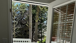 Eine geöffnete Tür, die auf eine Terrasse mit weißer Geländer und Gartenmöbeln führt.