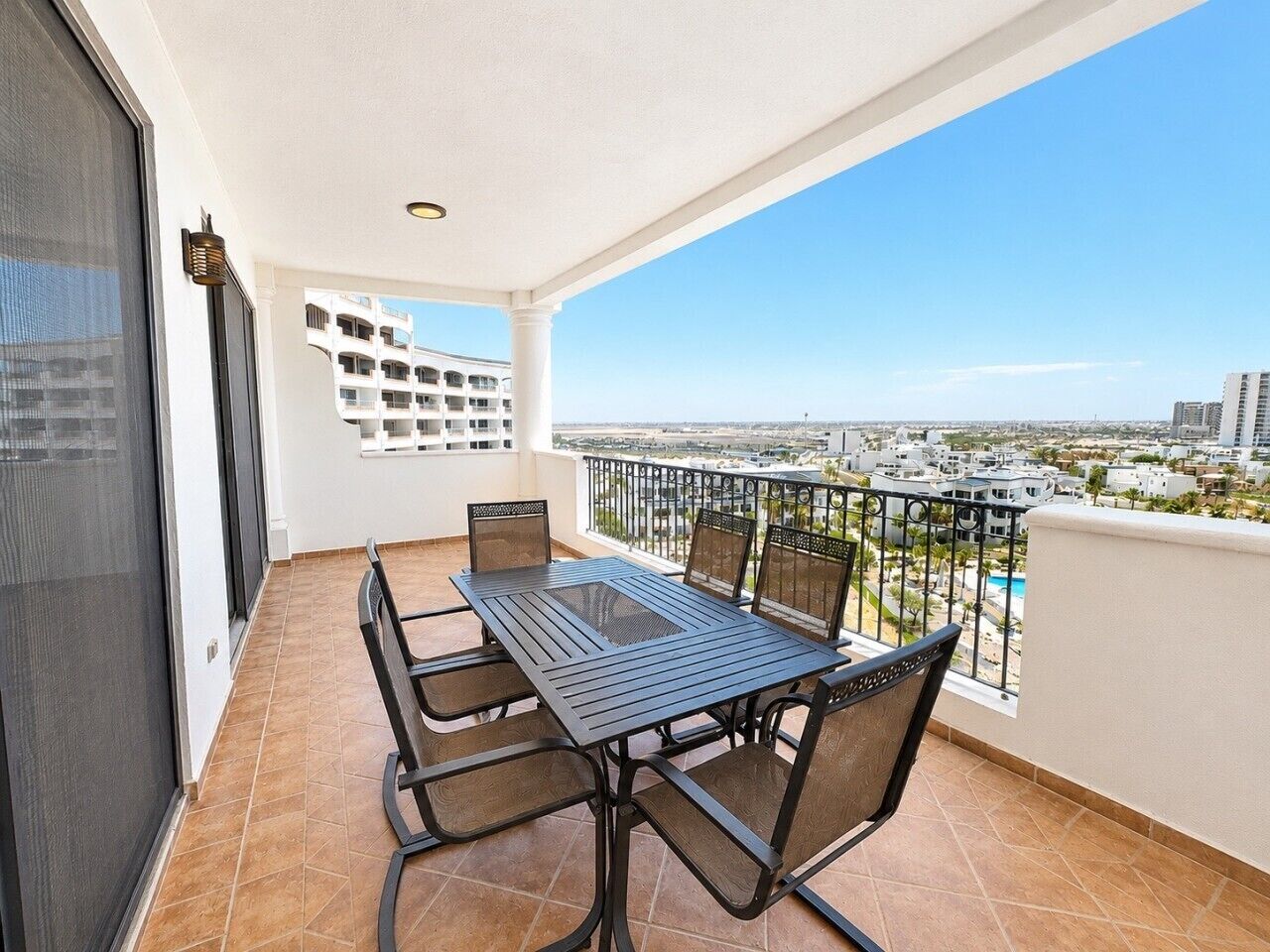Un balcone con tavolo e sedie, vista sulla città e un edificio sullo sfondo.