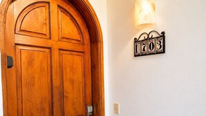 Une porte en bois au design traditionnel, un luminaire fixé au mur et une enseigne décorative avec des chiffres.
