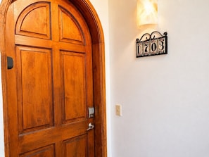 A wooden door with a traditional design, a wall-mounted light fixture, and a decorative sign with numbers. - Casa Blanca D703 Pet Friendly Ocean View Condo (Puerto Peñasco)