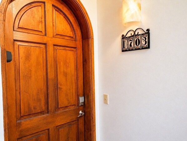 A wooden door with a traditional design, a wall-mounted light fixture, and a decorative sign with numbers. - Casa Blanca D703 Pet Friendly Ocean View Condo (Puerto Peñasco)