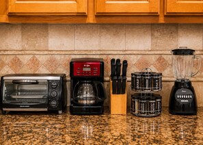 A kitchen with a toaster oven, coffee maker, knife block, and blender.