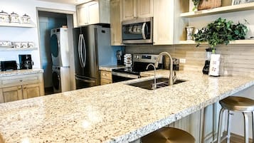 A modern kitchen with granite countertops, stainless steel appliances, and wooden cabinets.