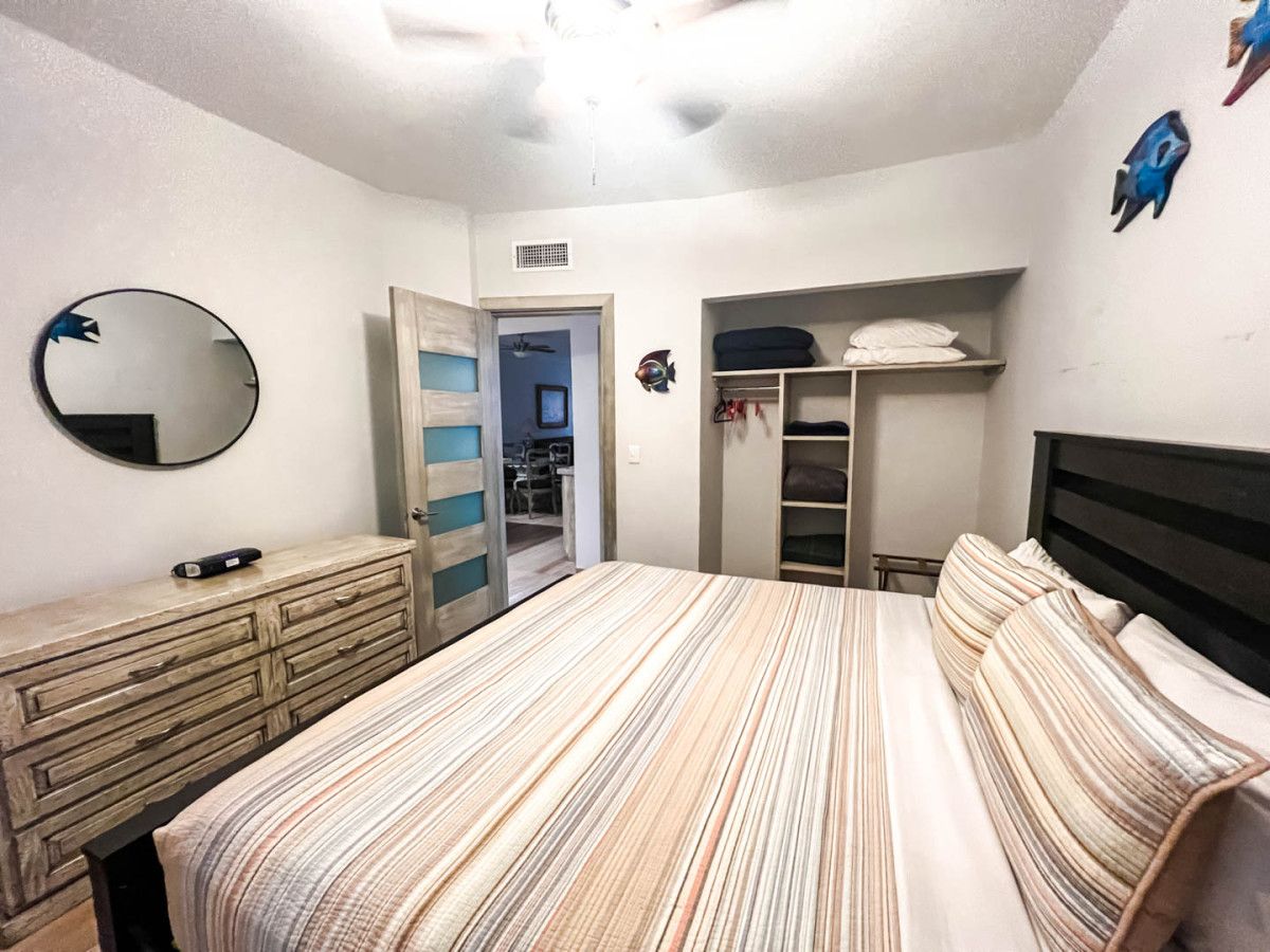 A bedroom with a bed, a dresser, a closet, and a mirror.