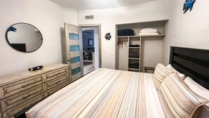A bedroom with a bed, a dresser, a closet, and a mirror.