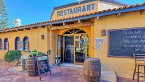 A restaurant with a signboard, outdoor seating, and a chalkboard menu.