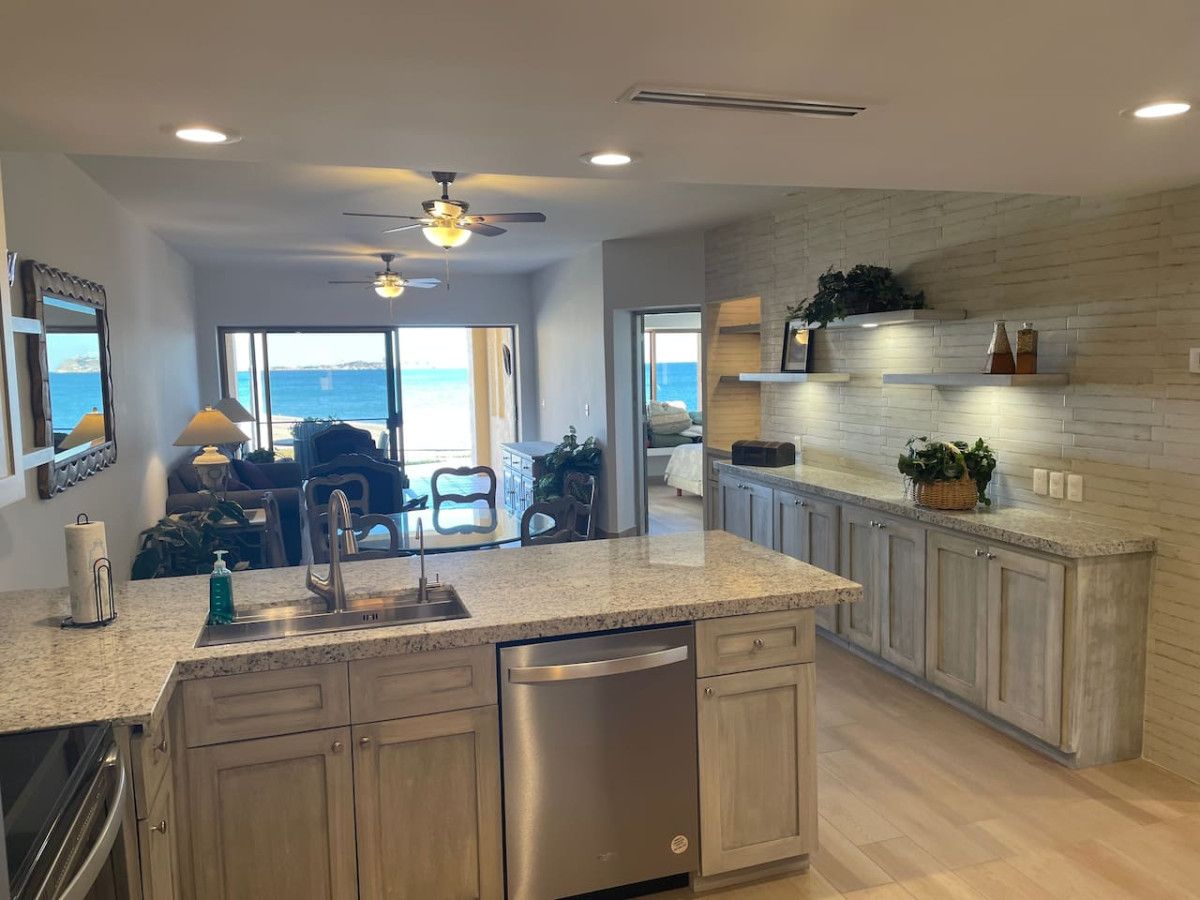 A modern kitchen with granite countertops, stainless steel appliances, and a view to the ocean.