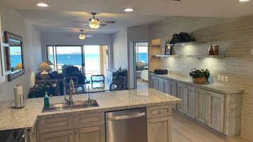A modern kitchen with granite countertops, stainless steel appliances, and a view to the ocean.