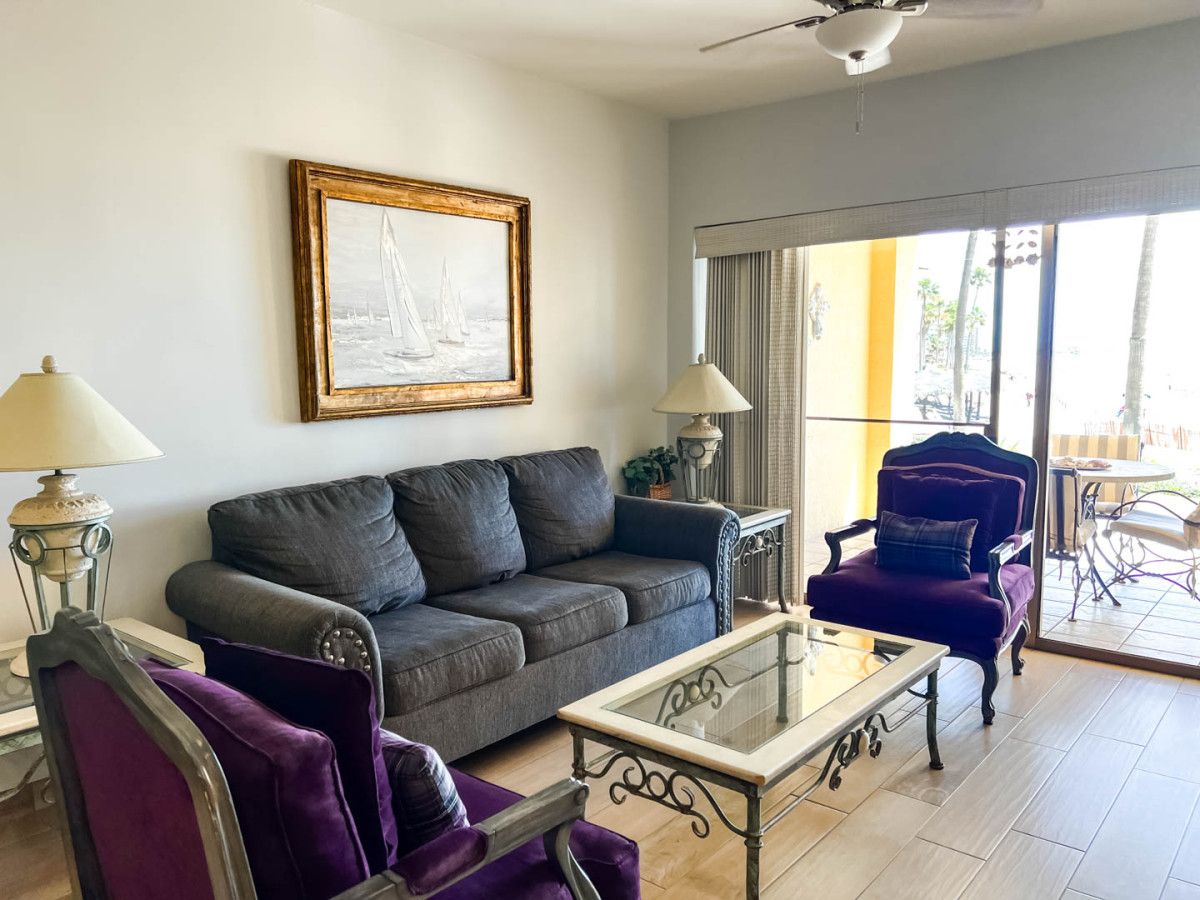 A living room with a sofa, armchairs, a coffee table, and a painting on the wall.