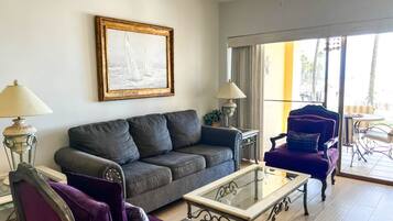 A living room with a sofa, armchairs, a coffee table, and a painting on the wall.