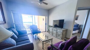 A living room with a sofa, armchair, coffee table, TV, and a cabinet.