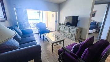 A living room with a sofa, armchair, coffee table, TV, and a cabinet.