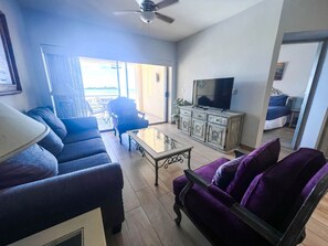 A living room with a sofa, armchair, coffee table, television, and a cabinet. - Princesa A101 Fresh Remodel, Directly on the Beach (Puerto Peñasco)