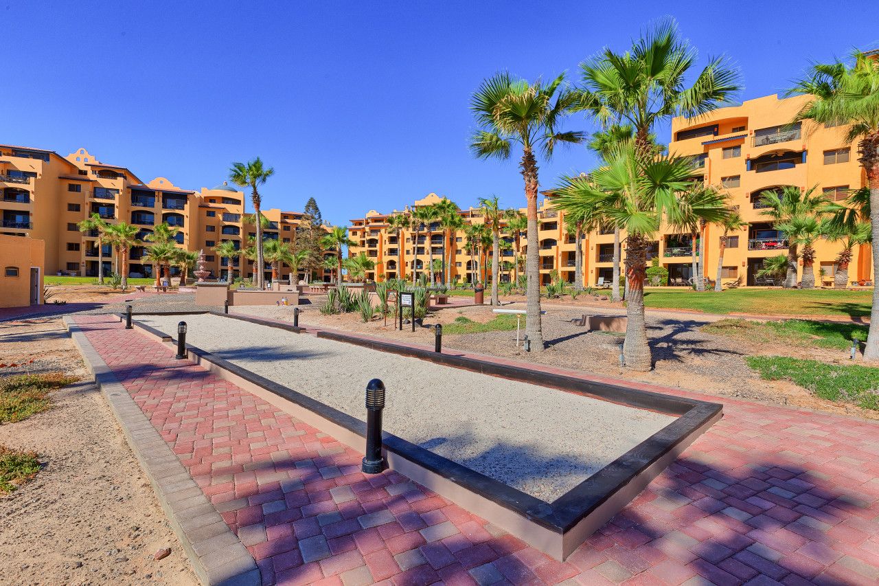 A hotel courtyard with palm trees, a pool, and multiple-story buildings.