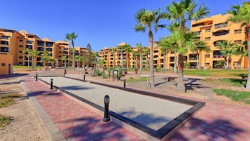 A hotel courtyard with palm trees, a pool, and multiple-story buildings.