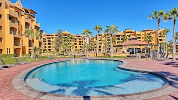 A swimming pool with a curved edge, surrounded by a brick walkway.