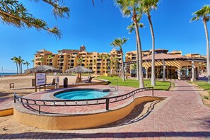 A resort with a swimming pool, palm trees, and a beach view.