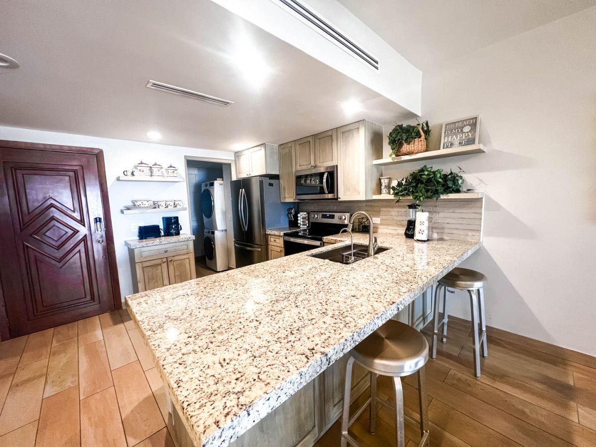 Eine moderne Küche mit Granit Arbeitsplatten, Edelstahlgeräten und Holzschränken.