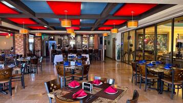 A spacious restaurant with multiple dining areas, a bar, and a view of the cityscape.