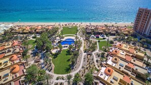 Un complexe hôtelier doté d’une piscine, de palmiers et offrant une vue sur la plage.