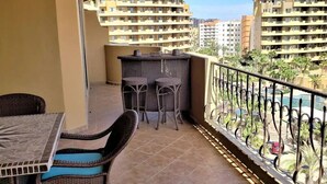 Un balcon avec une table et des chaises, un petit coin bar et une vue sur les bâtiments environnants.