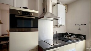 A compact kitchen with a built-in oven, a microwave, a stove, a sink, and a built-in washing machine.