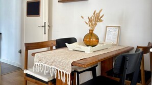 A dining area with a wooden table, chairs, a vase, and a framed welcome sign.