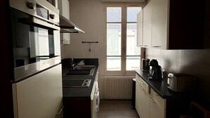 A narrow kitchen with a window, a built-in oven, and a sink.