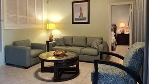 A living room with a wooden ceiling, a sofa, a round coffee table, and a patterned armchair. - Private Pool & Garden - Tranquil Retreat (Paradise Island)
