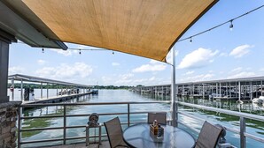 Ein Sitzbereich im Freien mit Tisch und Stühlen mit Blick auf einen Hafen und Boote.