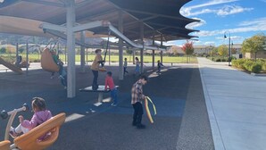 Un patio de juegos cubierto con diversos juegos y un camino pavimentado.