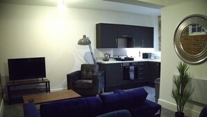 A living room with a sofa, a TV, a coffee table, and a kitchen area with cabinets and appliances. - Old Dutch Embassy by Guestz (Kingston-upon-Hull)