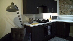 A compact kitchen with black cabinets, a microwave, a kettle, and a modern lamp. - Old Dutch Embassy by Guestz (Kingston-upon-Hull)
