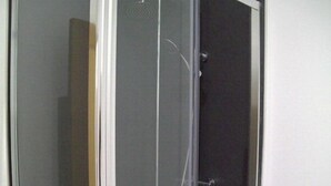 A glass-enclosed shower stall with a white door, a showerhead, and a handheld shower attachment. - Old Dutch Embassy by Guestz (Kingston-upon-Hull)