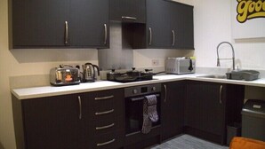 A compact kitchen with dark cabinets, a microwave, a toaster, and a kettle. - Old Dutch Embassy by Guestz (Kingston-upon-Hull)