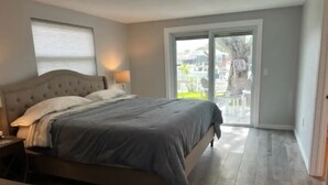 A bedroom with a large bed, a nightstand, and a window. - Summer Fun! New Port Richey Fl

 (New Port Richey)