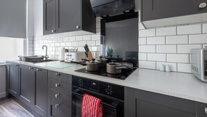 A modern kitchen with dark cabinets, a white countertop, a stove, and a microwave. - Binding House by Guestz (Kingston upon Hull)