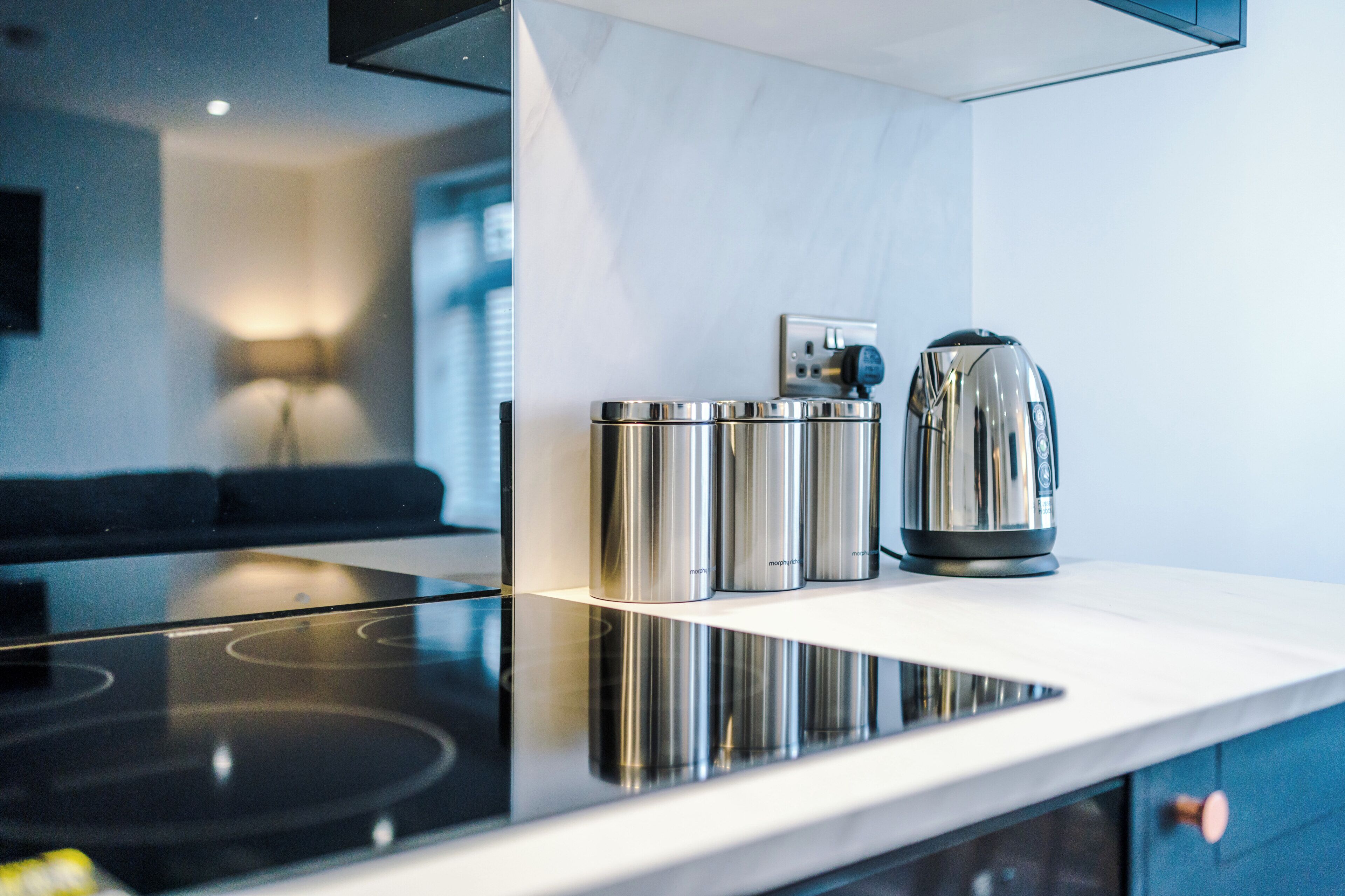 Een moderne keuken met een zwart inductiekookveld, roestvrijstalen apparatuur en een wit aanrecht.
