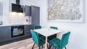 Una cucina moderna con forno integrato, un tavolo da pranzo con sedie e un grande quadro astratto appeso al muro.