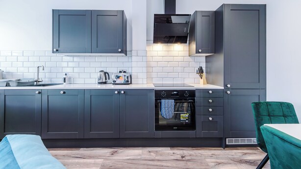 Una cucina moderna con mobili grigi, forno integrato e microonde.