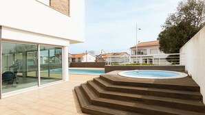 Un espace extérieur moderne doté d’une piscine, d’escaliers en bois et d’une porte vitrée donnant sur un patio abrité.