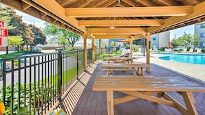 A wooden deck with picnic tables, a pool, and a fenced area with greenery. - Lakefront Port Clinton Condo w/ Boat Dock & Slip! (Port Clinton)