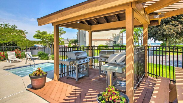 A covered outdoor area with a pool, barbecue grills, and lounge chairs. - Lakefront Port Clinton Condo w/ Boat Dock & Slip! (Port Clinton)