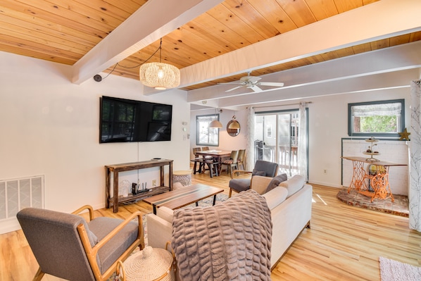 Relax in this spacious living area with a high ceiling, featuring a large flat-screen TV, dining table, and comfortable seating area.