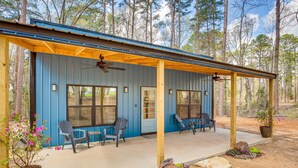 A blue cabin with a covered porch, two windows, and two chairs. - Winnsboro Barndominium w/ Fire Pit & Large Deck! (Winnsboro)
