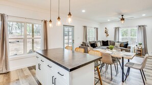 A spacious kitchen with a large island, dining area with chairs, and a sofa in the background. - Winnsboro Barndominium w/ Fire Pit & Large Deck! (Winnsboro)