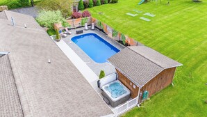 A backyard with a swimming pool, hot tub, and a wooden deck. - Lakeview w/Pool, Hot Tub, Firepit, Gameroom, Golf! (Penn Yan)